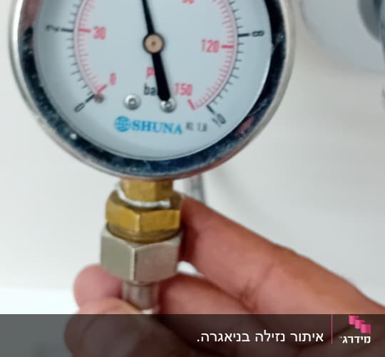 מד לחץ מים עם יד מחזיקה בצינור